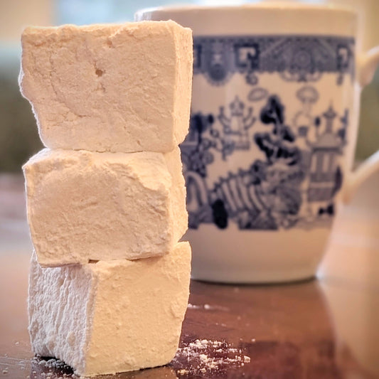 Pile of vanilla bean marshmallows, in front of a mug